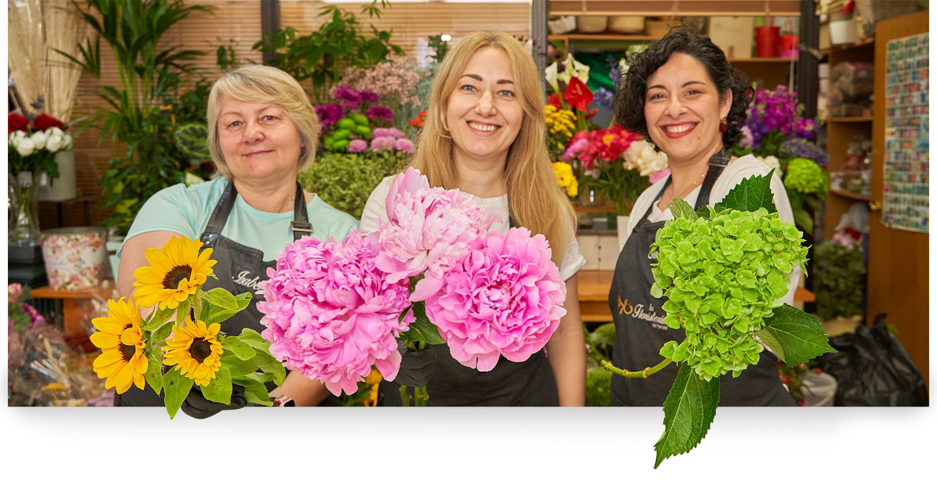 profesionales detrás de mostrador enseñando flores y sonriendo 