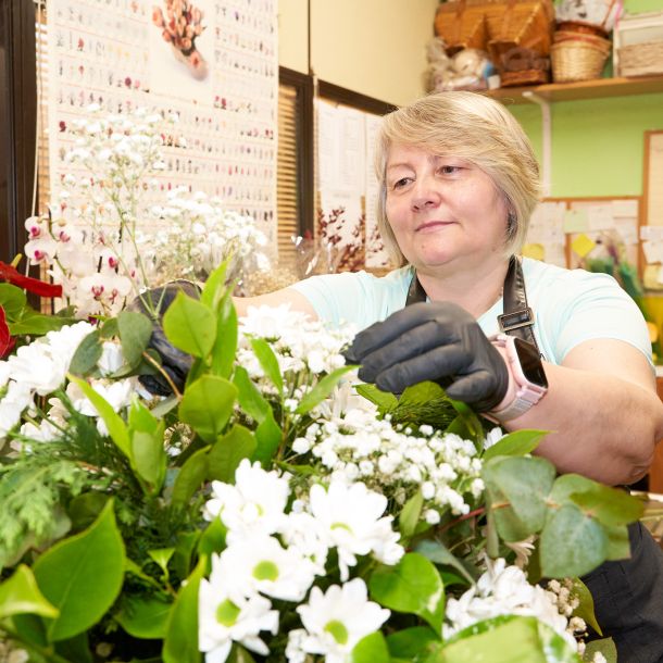 profesional arreglando flores para ramo y sonriendo 